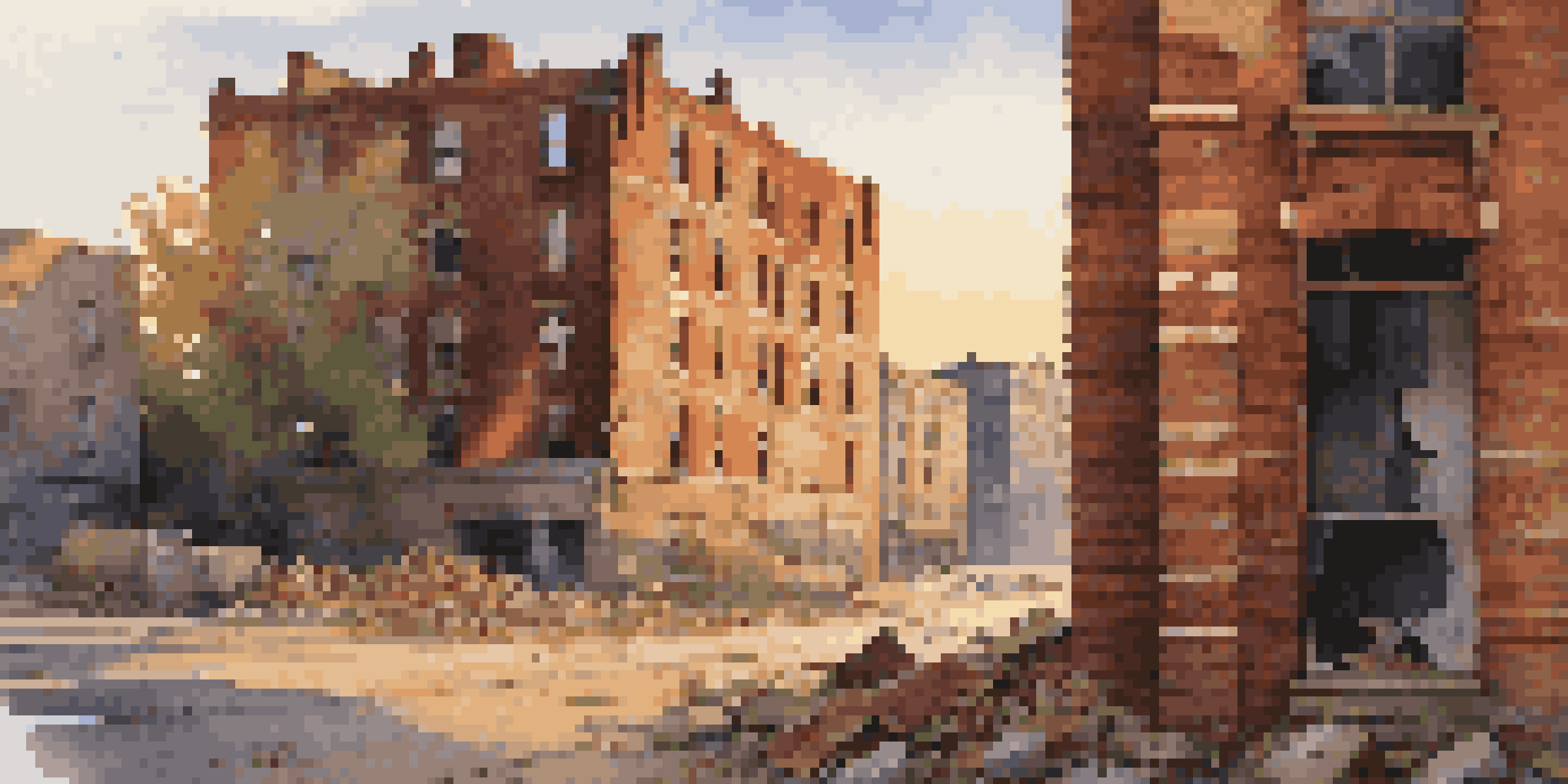 An abandoned building at dusk with crumbling walls and broken windows, illuminated by the golden hour light.
