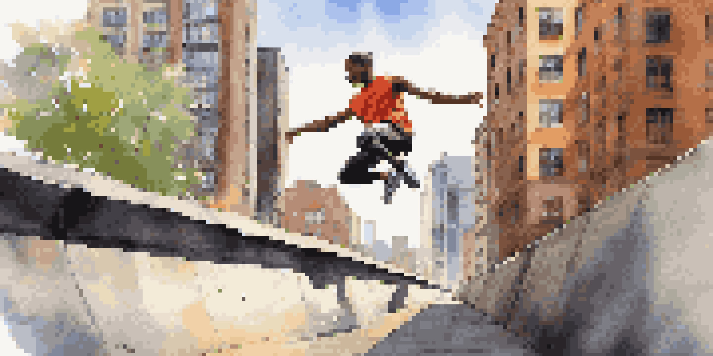 A parkour athlete performing a vault over a concrete barrier in a sunny urban environment, with tall buildings and street art in the background.