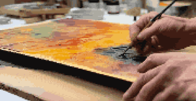 A close-up view of an encaustic painting process, with colorful beeswax layers and a palette under warm lighting.