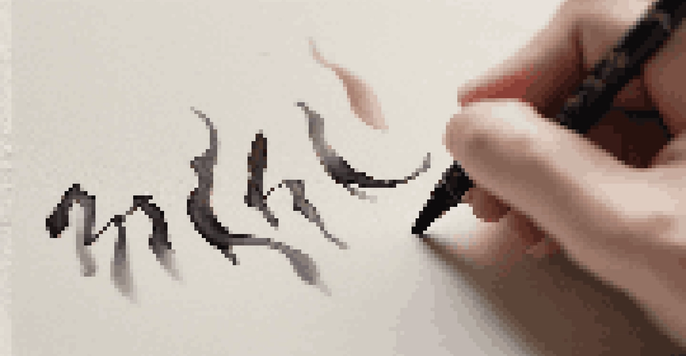 A close-up of a hand demonstrating calligraphy with detailed strokes on paper.