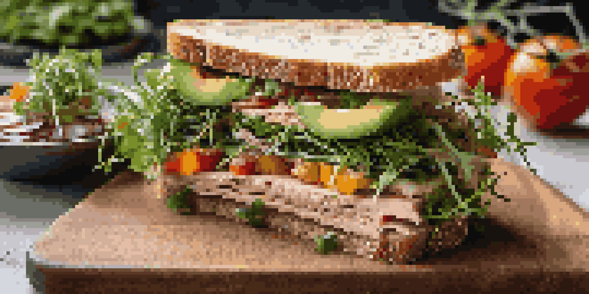 A gourmet sandwich with sourdough bread, heirloom tomatoes, arugula, avocado, and smoked turkey, garnished with microgreens on a wooden cutting board.