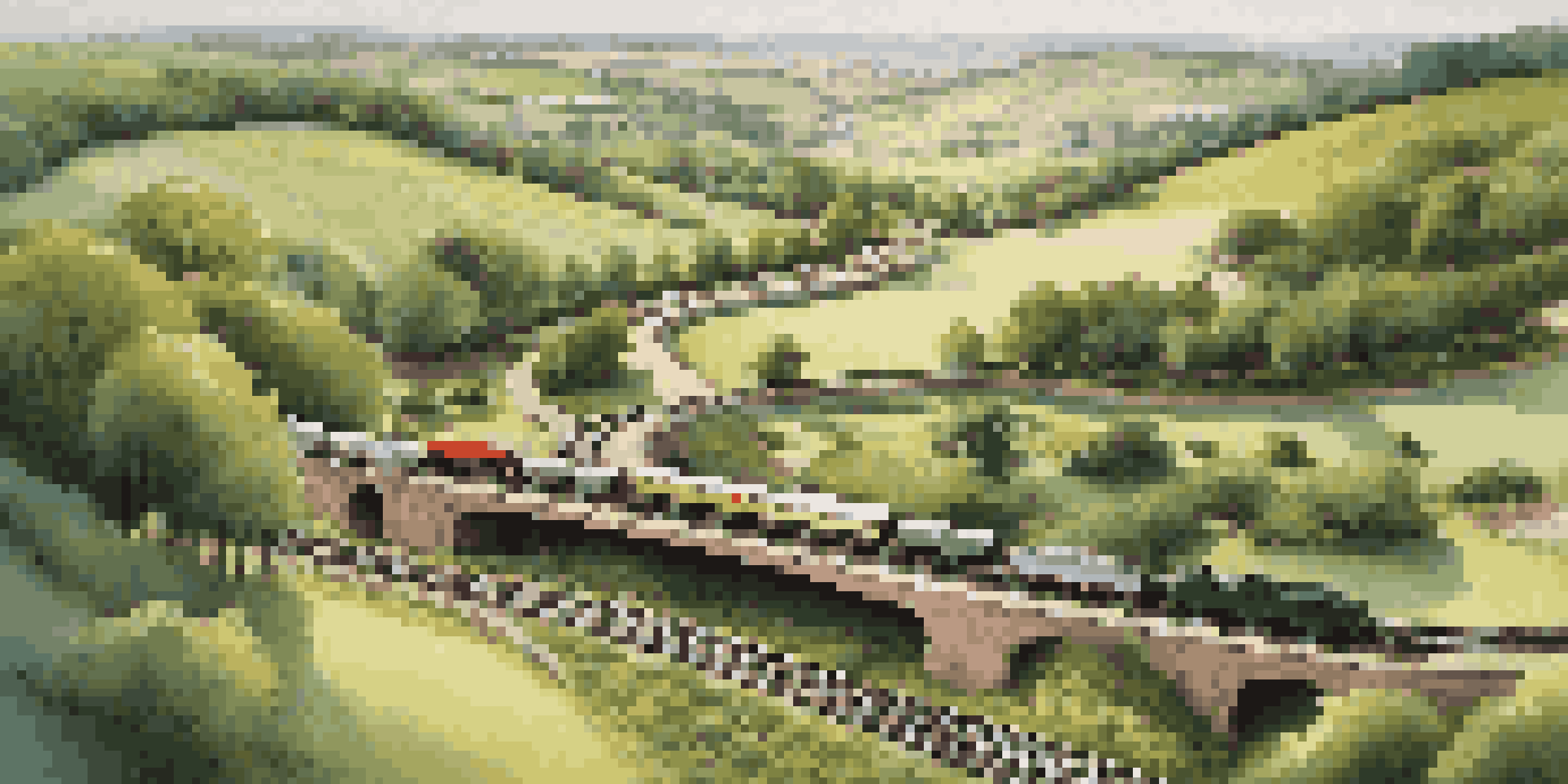 A miniature model railroad scene with straight and curved tracks, surrounded by green fields and trees, showcasing a small train on the tracks.