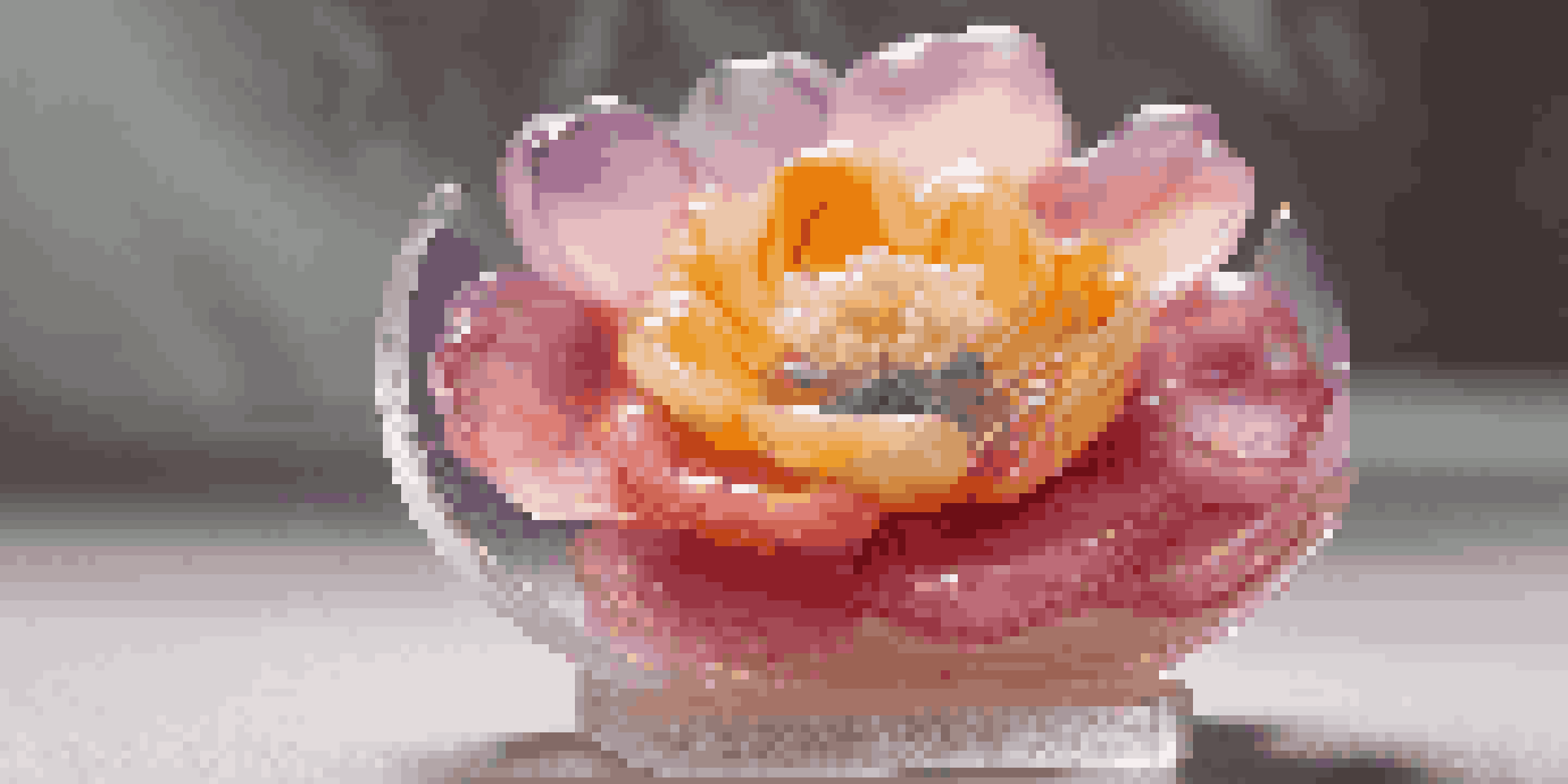 A soap sculpture resembling a delicate flower with intricate petals, displayed on a clear stand under soft lighting.