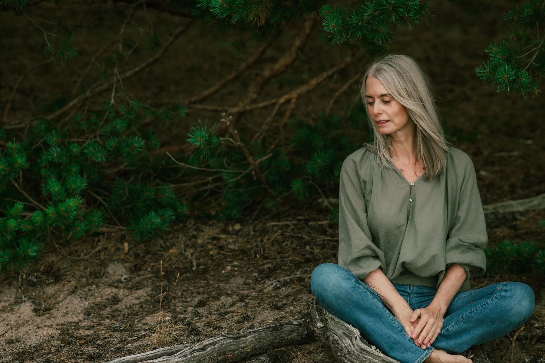 En kvinna sitter i skogen och funderar
