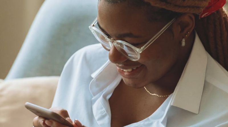 A woman smiling while using her phone