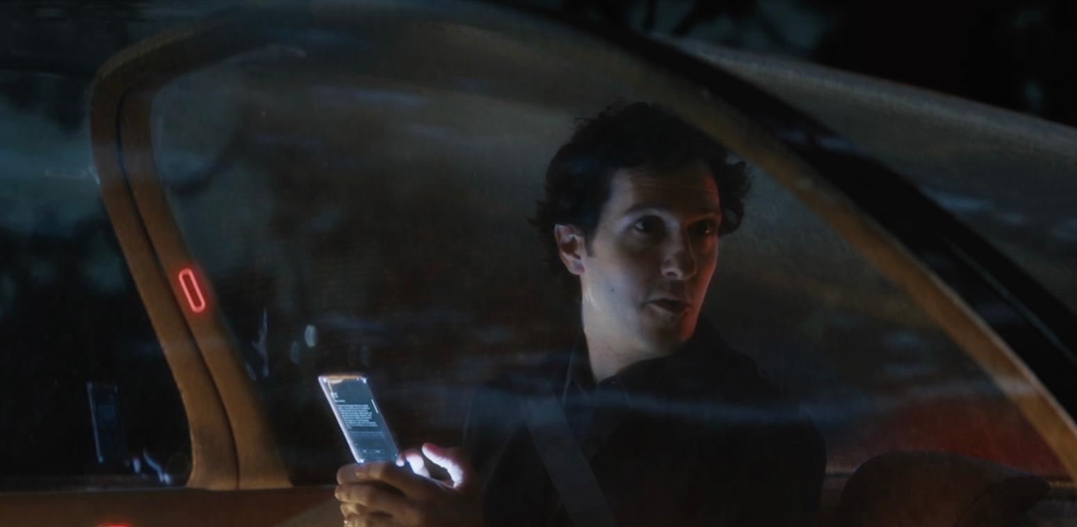 Man sitting in smart car holding phone and looking out of the window suspiciously