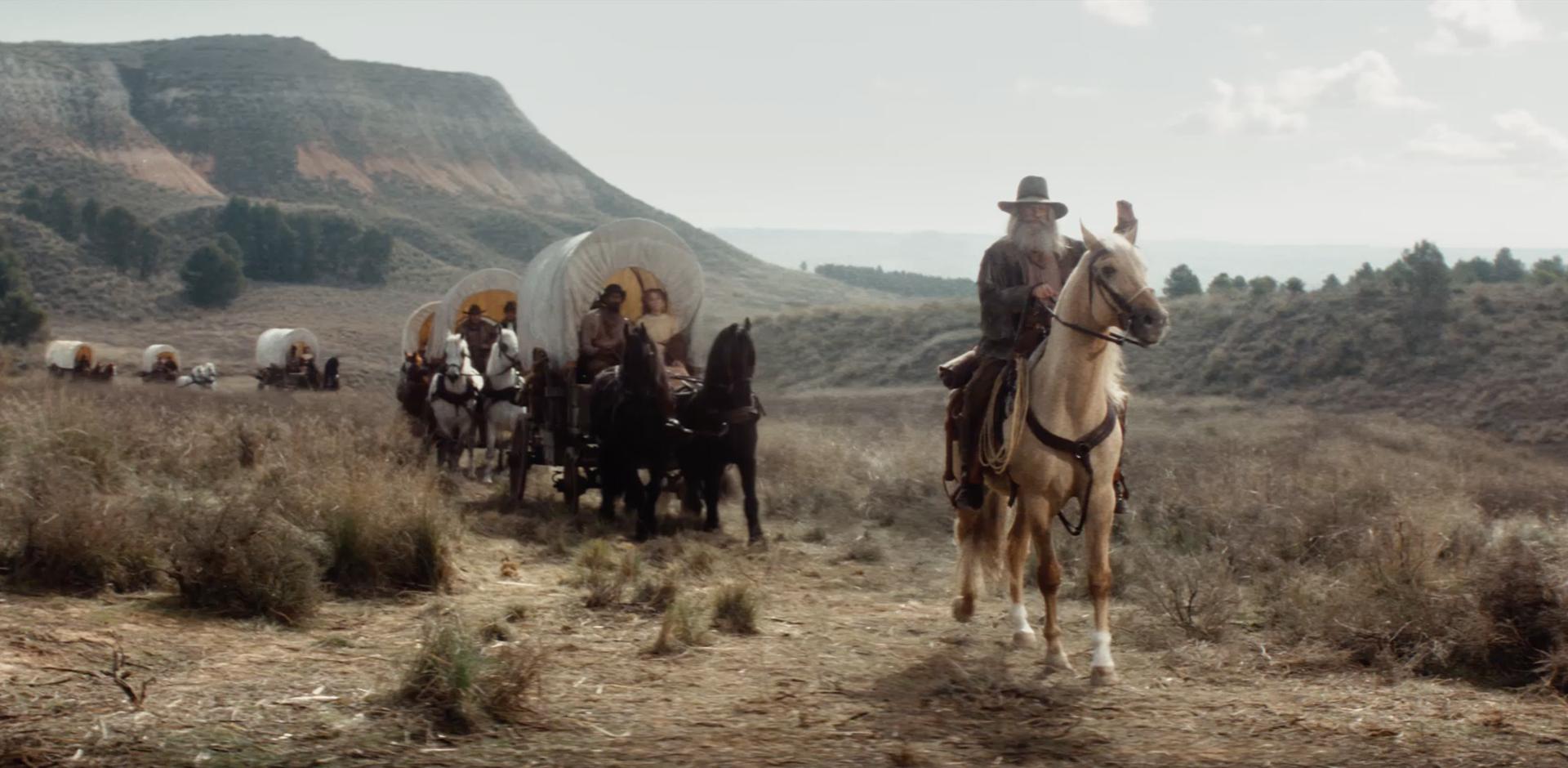 Man on horse leading horse-drawn wagons through the Oregon Trail