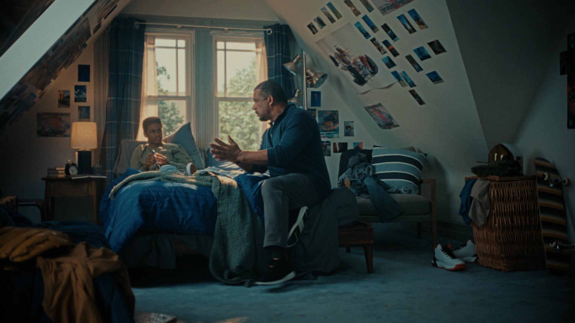 Father talking to son sitting on bed in son's room