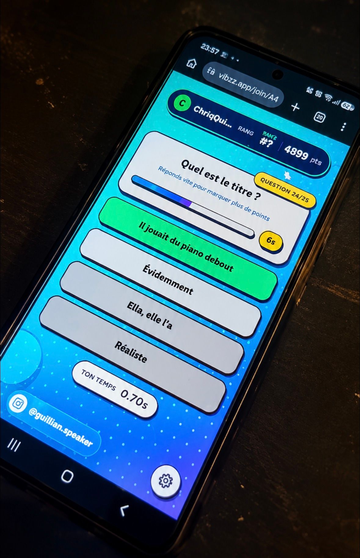 Un téléphone posé sur une table affiche une question musicale et les réponses proposées dans Vibzz.
