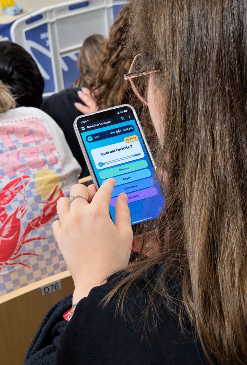 Participant répondant à un blind test Vibzz depuis son téléphone pendant une animation de groupe.
