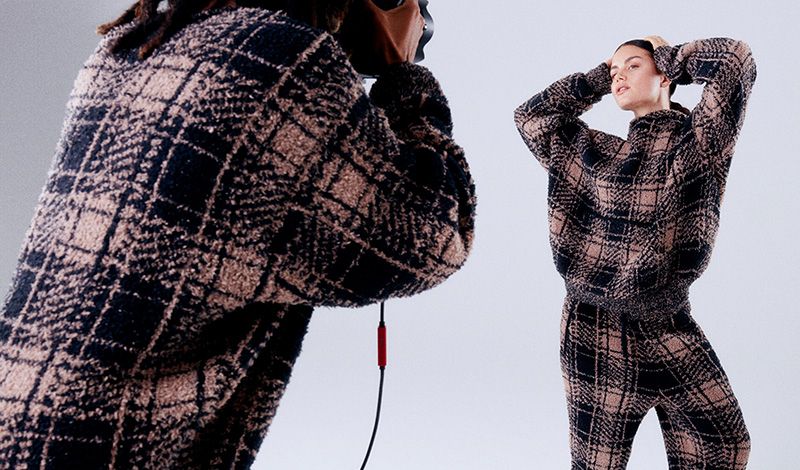 Models pose wearing the new SKIMS Cozy knit unisex in plaid.