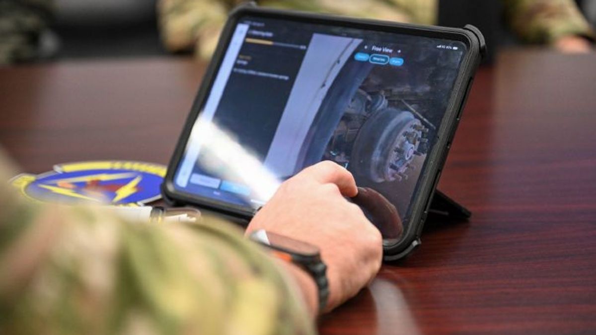 person in a military uniform shot from arm's length, interacting with the steering axle 3d model on a tablet