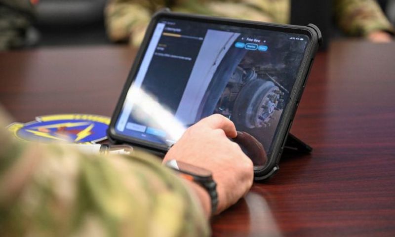 person in a military uniform shot from arm's length, interacting with the steering axle 3d model on a tablet