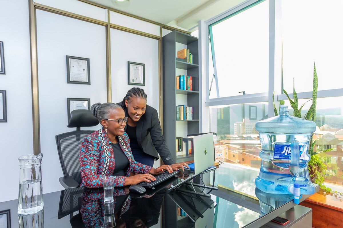 Two colleagues looking at a laptop beside a water dispenser