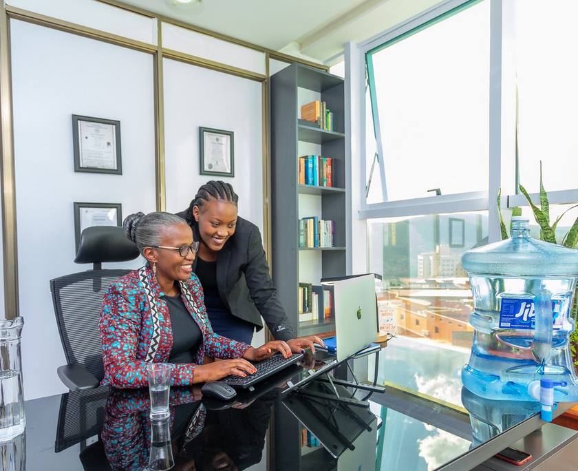 Two colleagues looking at a laptop beside a water dispenser