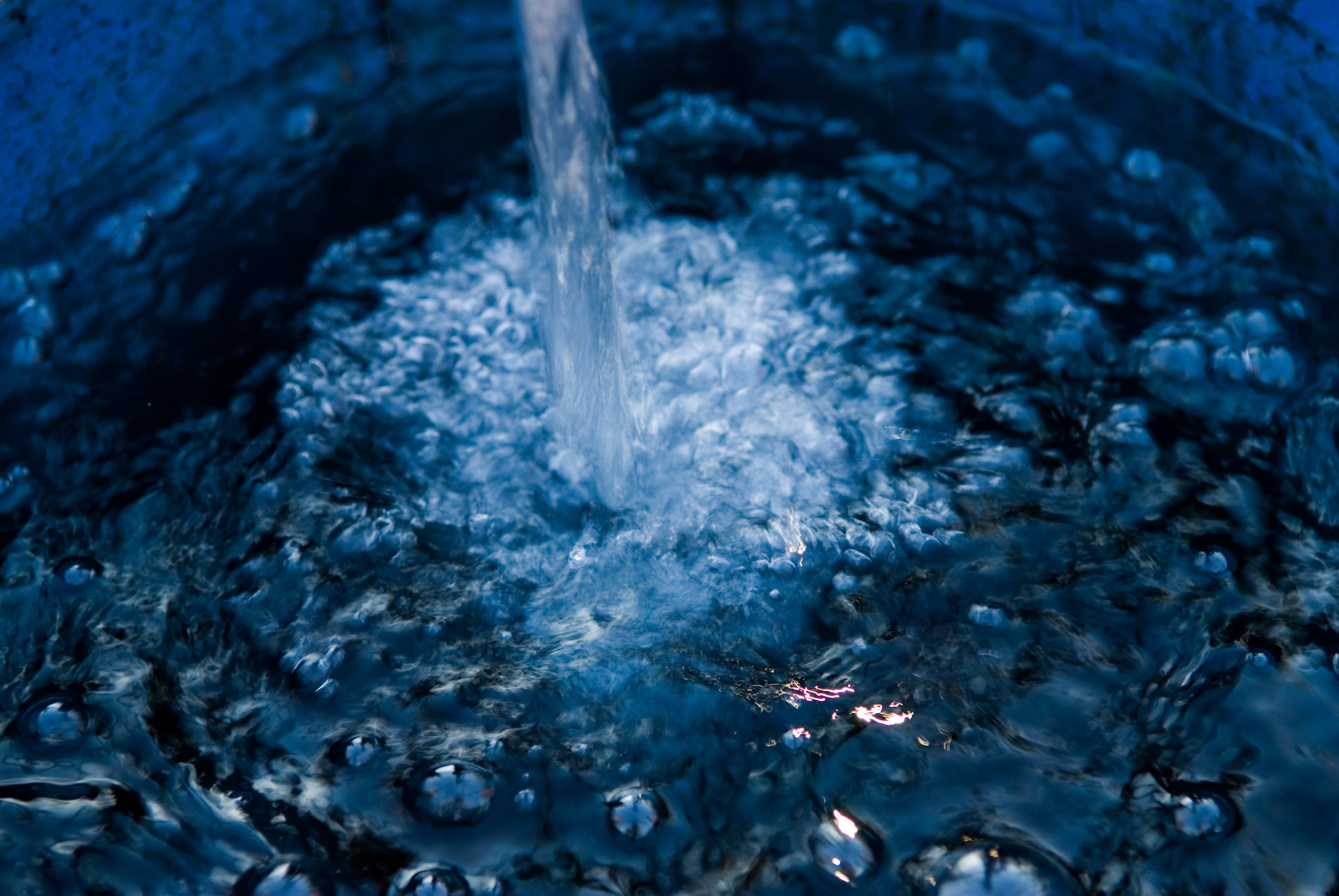 Water pours into a container and splashes across the surface.