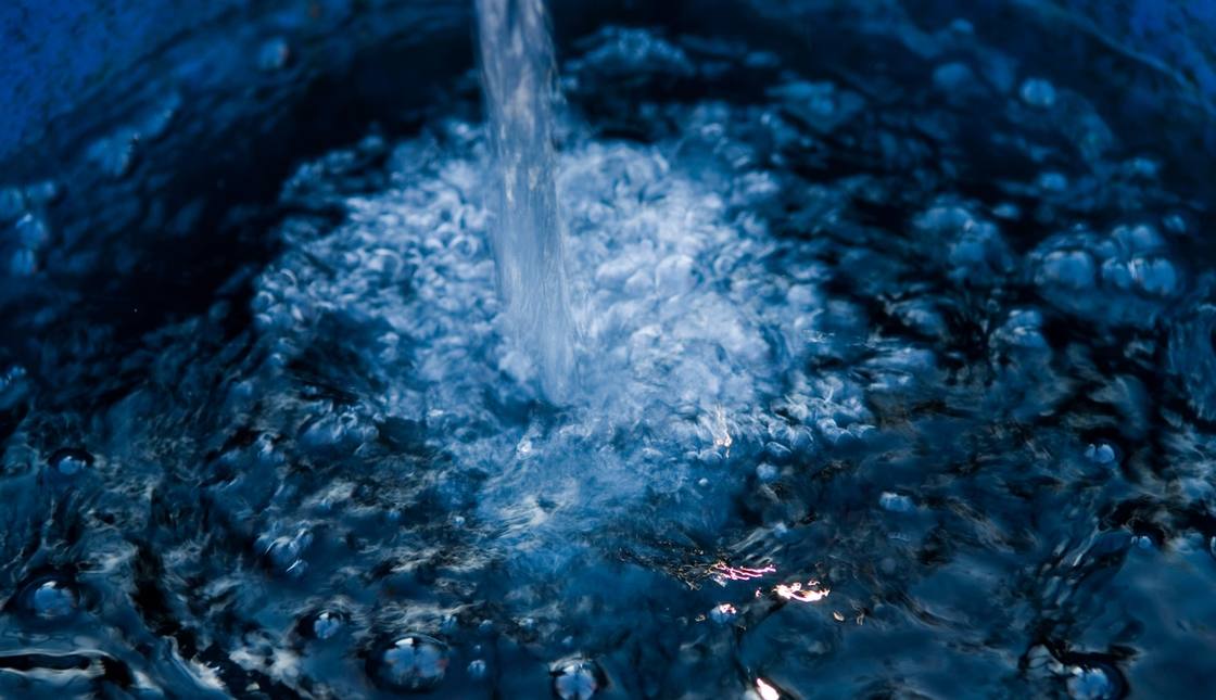 Water pours into a container and splashes across the surface.