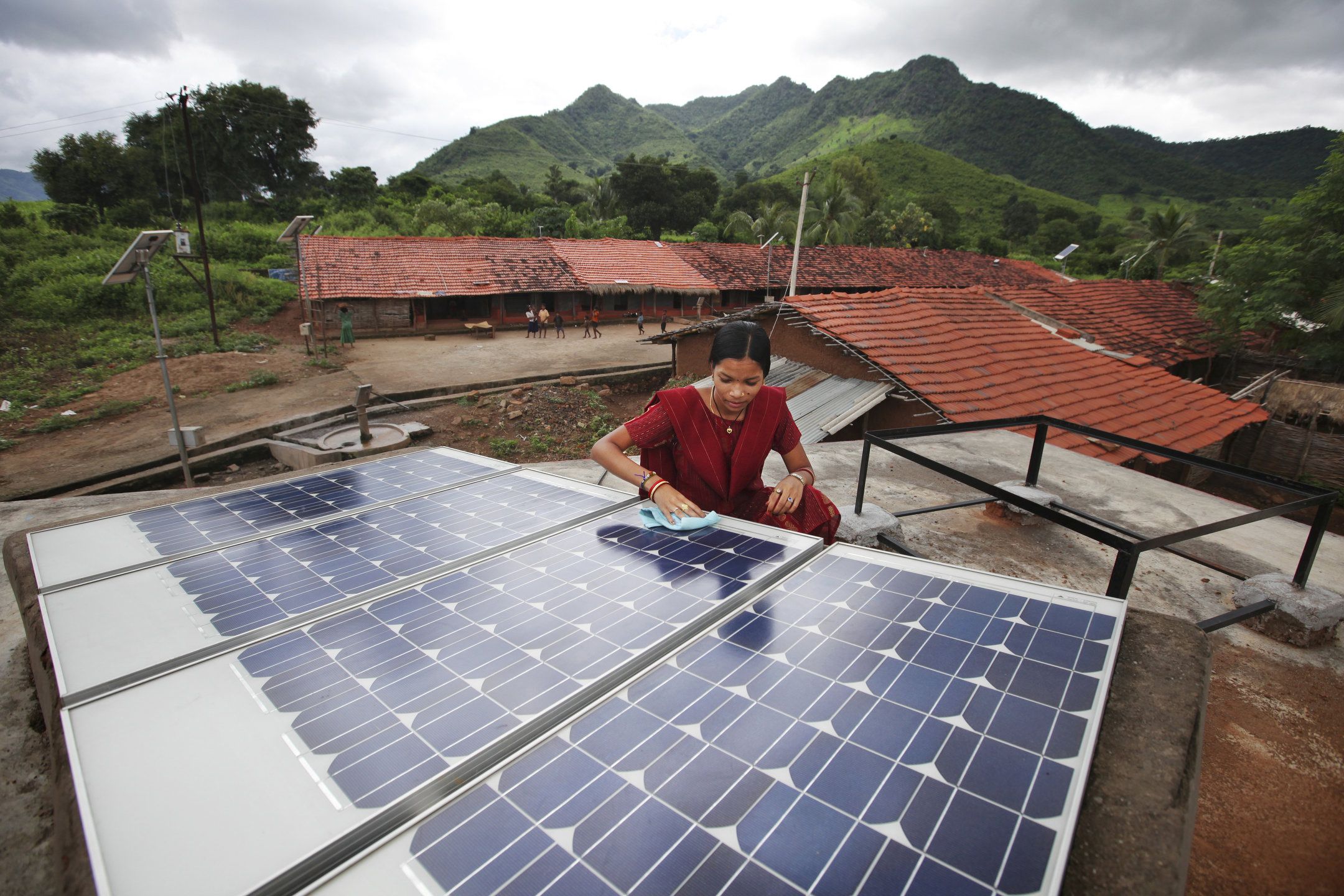 A woman cleans solar panels on a roof in rural India.