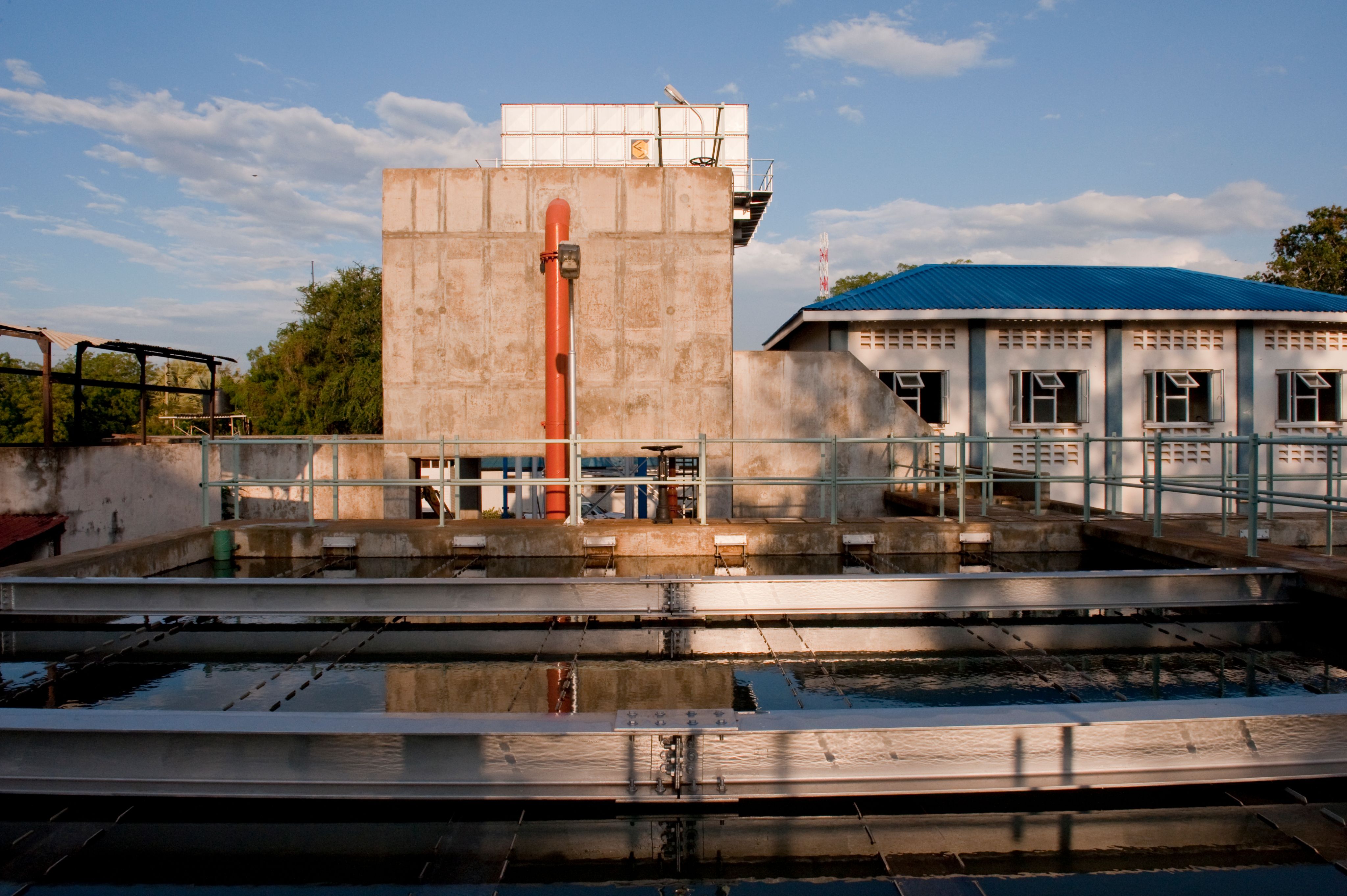 Waterzuiveringsinstallatie met bassins en bijgebouwen bij zonsondergang
