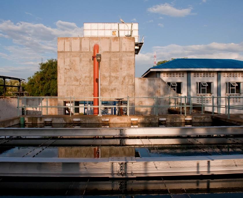 Waterzuiveringsinstallatie met bassins en bijgebouwen bij zonsondergang