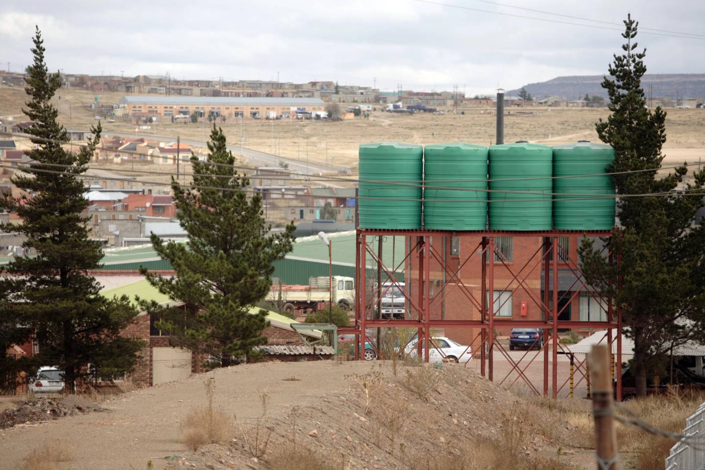 Green water tanks on a steel frame above a town in Lesotho.