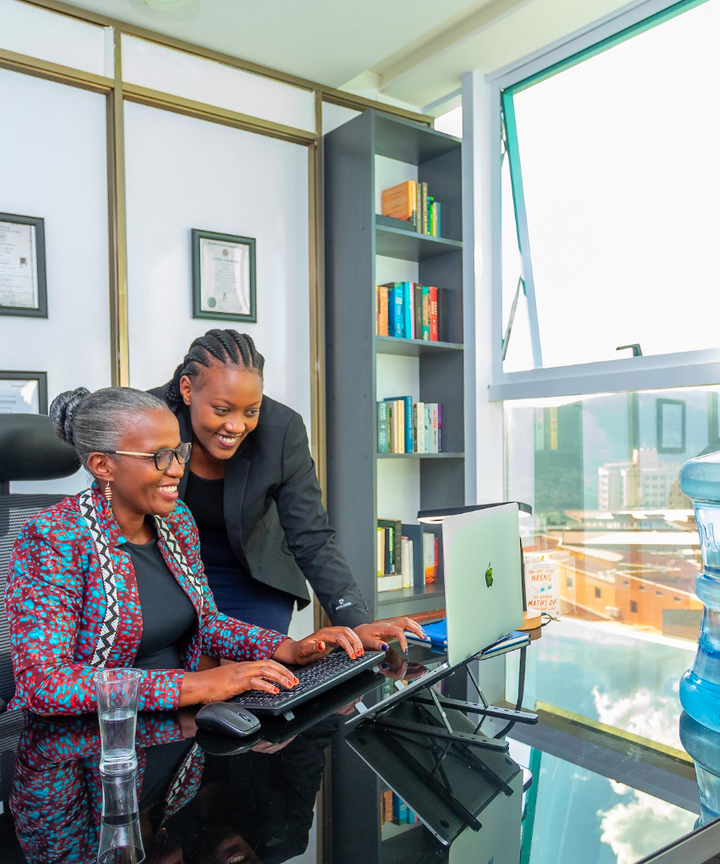 Two colleagues going through figures on a laptop in an office, with a water dispenser beside them.