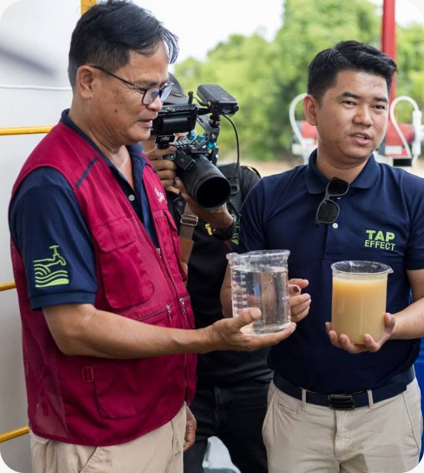Two colleagues holding up a clear and a cloudy water sample side by side