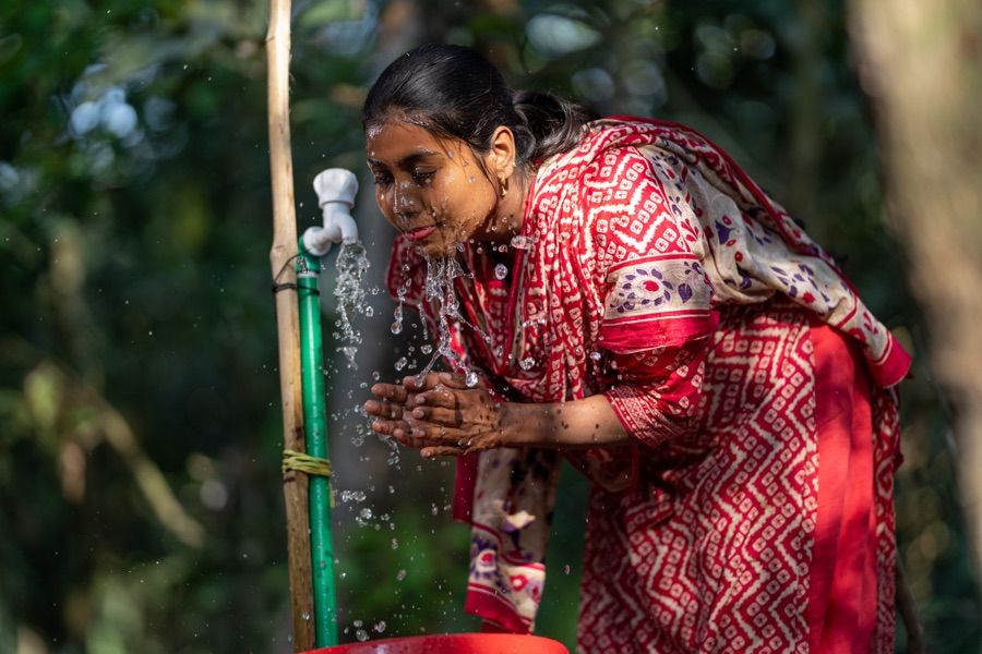A woman fills a jerrycan at a tap.