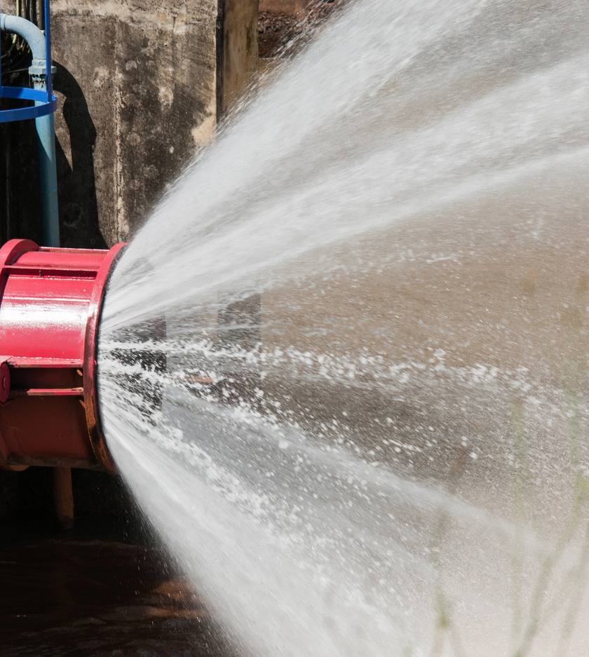 Krachtige waterstraal uit een rode brandkraan