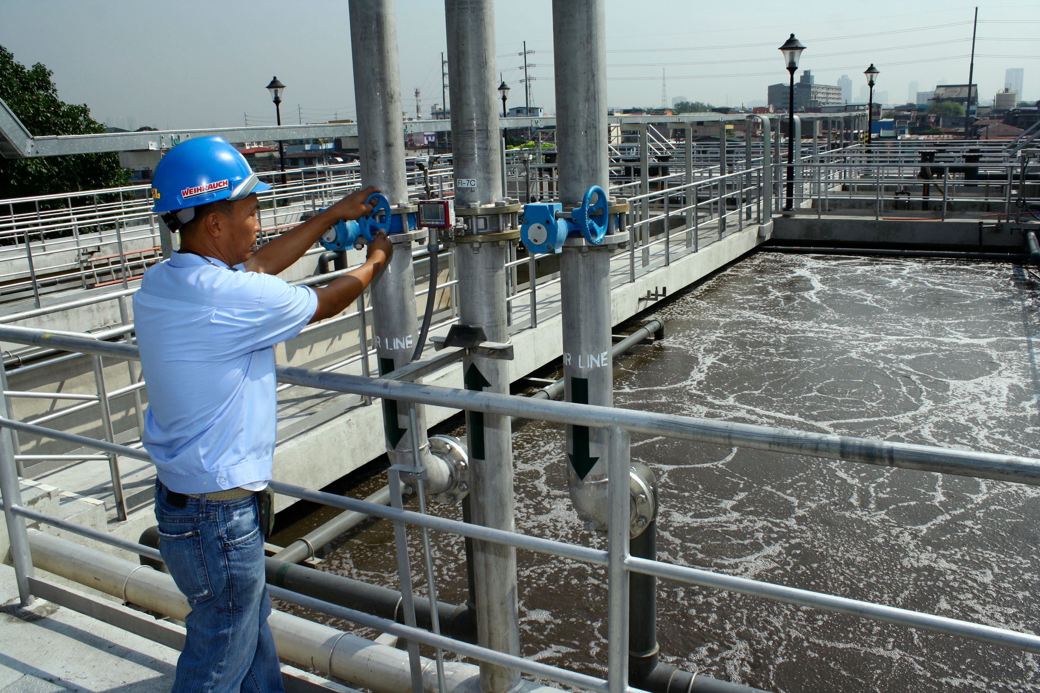 An engineer in a hard hat operating valves at a water treatment plant.