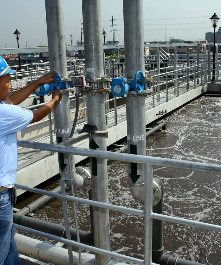 An engineer in a hard hat operating valves at a water treatment plant.