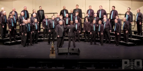 Great Lakes Chorus singing with trophy on stage