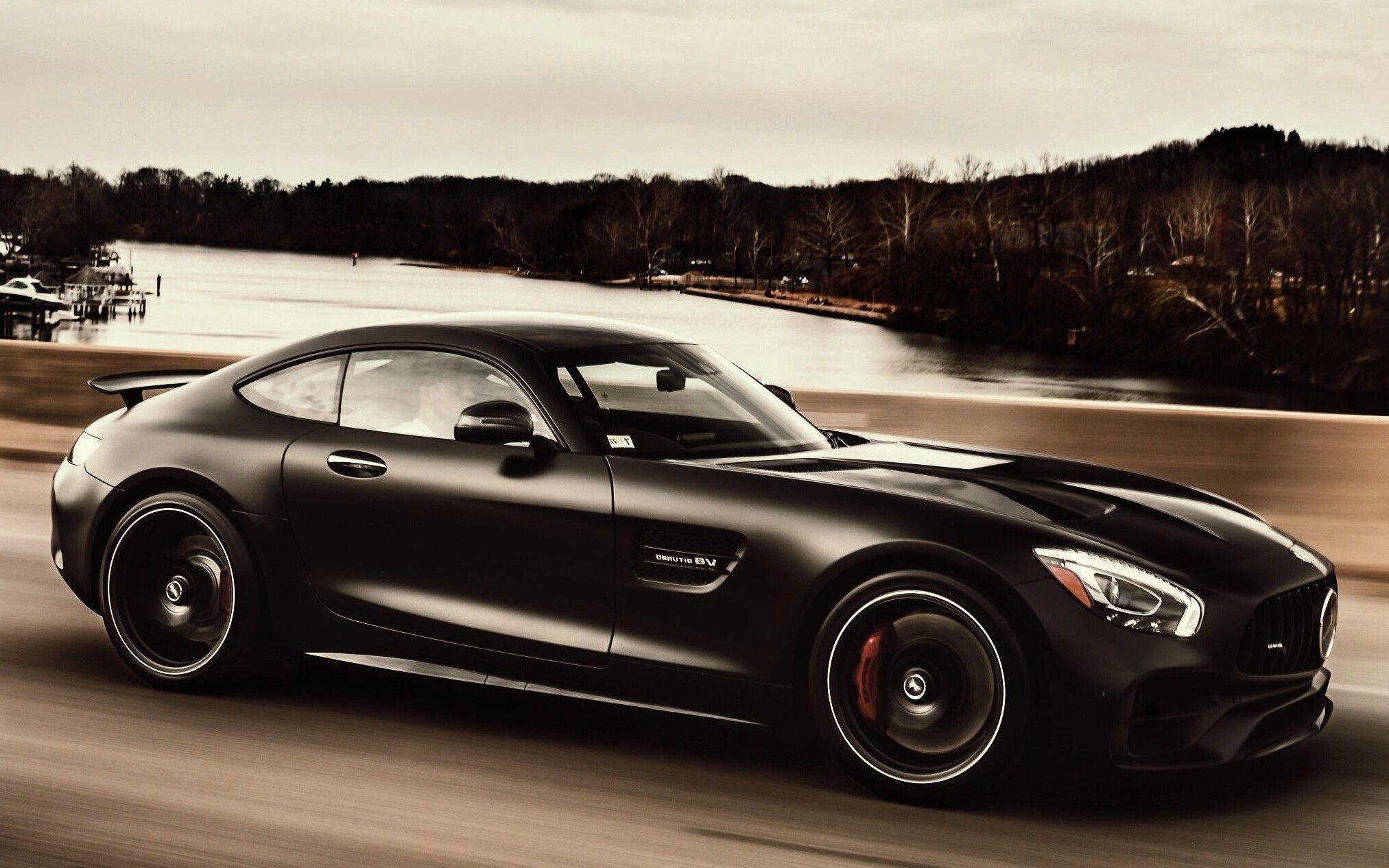 A black Mercedes-AMG GT on a road by a river, the photograph from the hero of the Auto-Klinika site