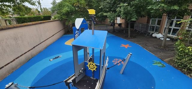 Structure de jeu en forme de bateau sur sol amortissant bleu avec motifs marins