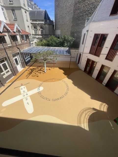 Cour d'école avec sol souple amortissant et motifs de jeux au sol