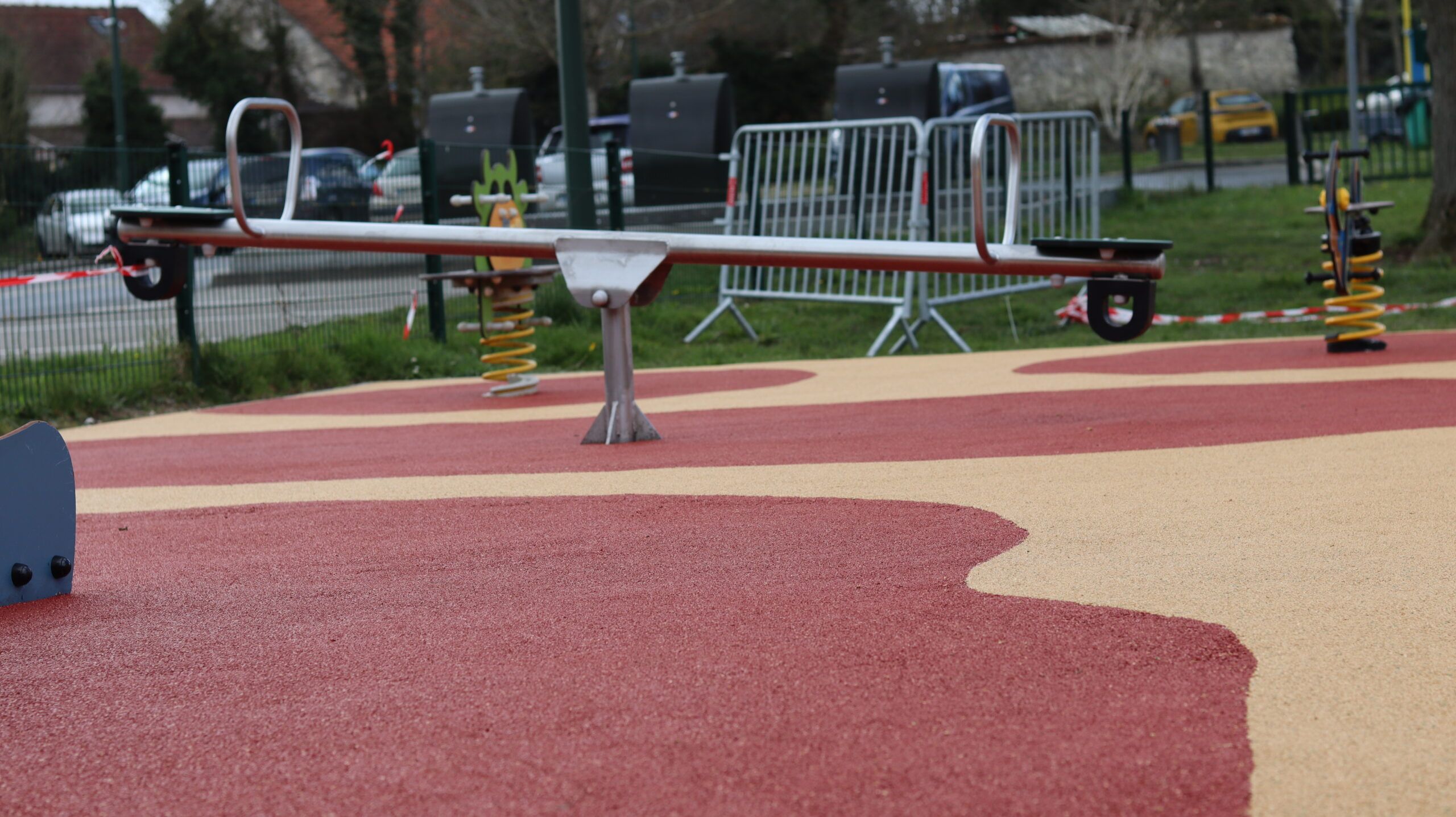 Balançoire sur sol amortissant EPDM rouge et beige en cour d'école