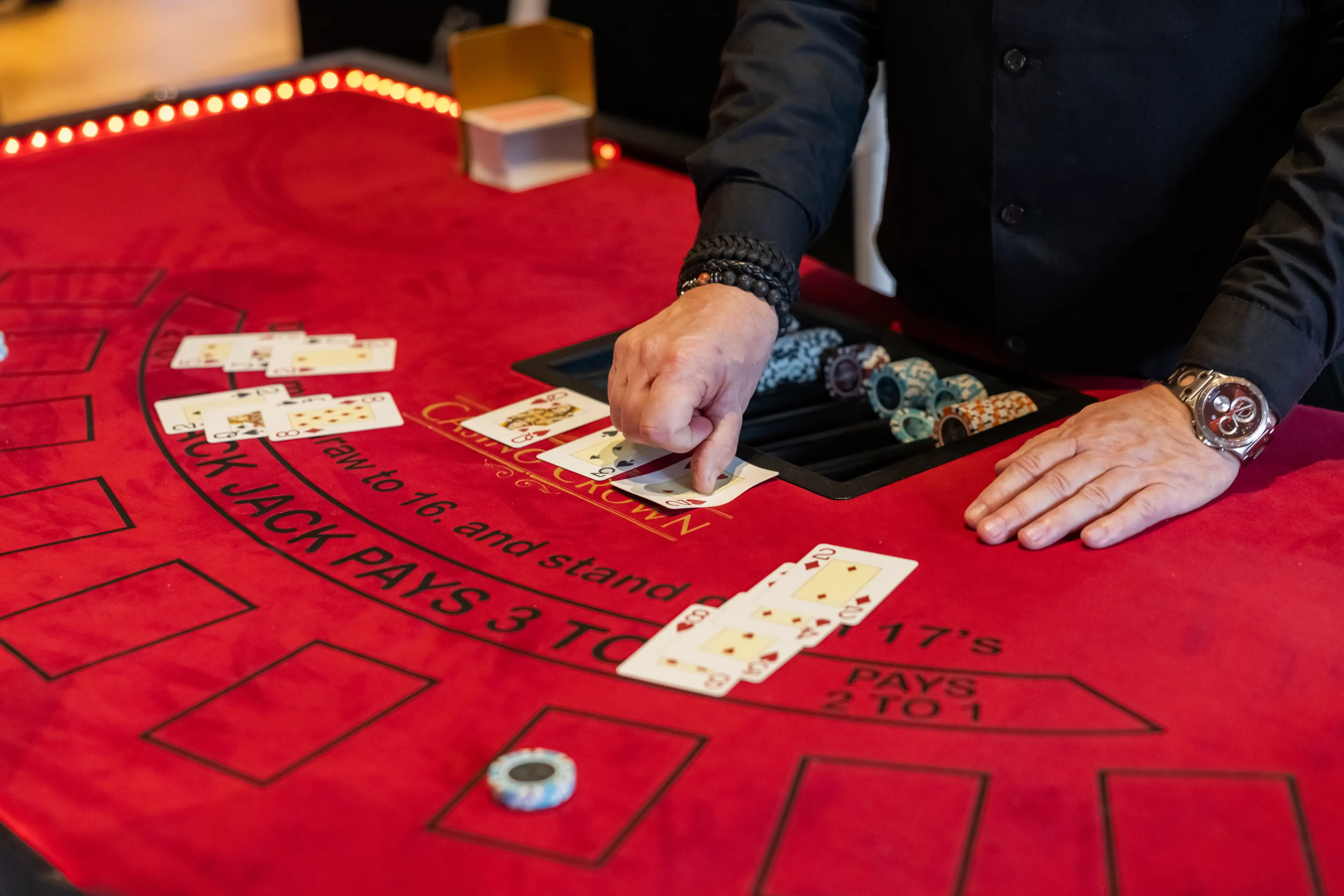Casino Crown dealer håndterer kort ved rødt black jack-bord