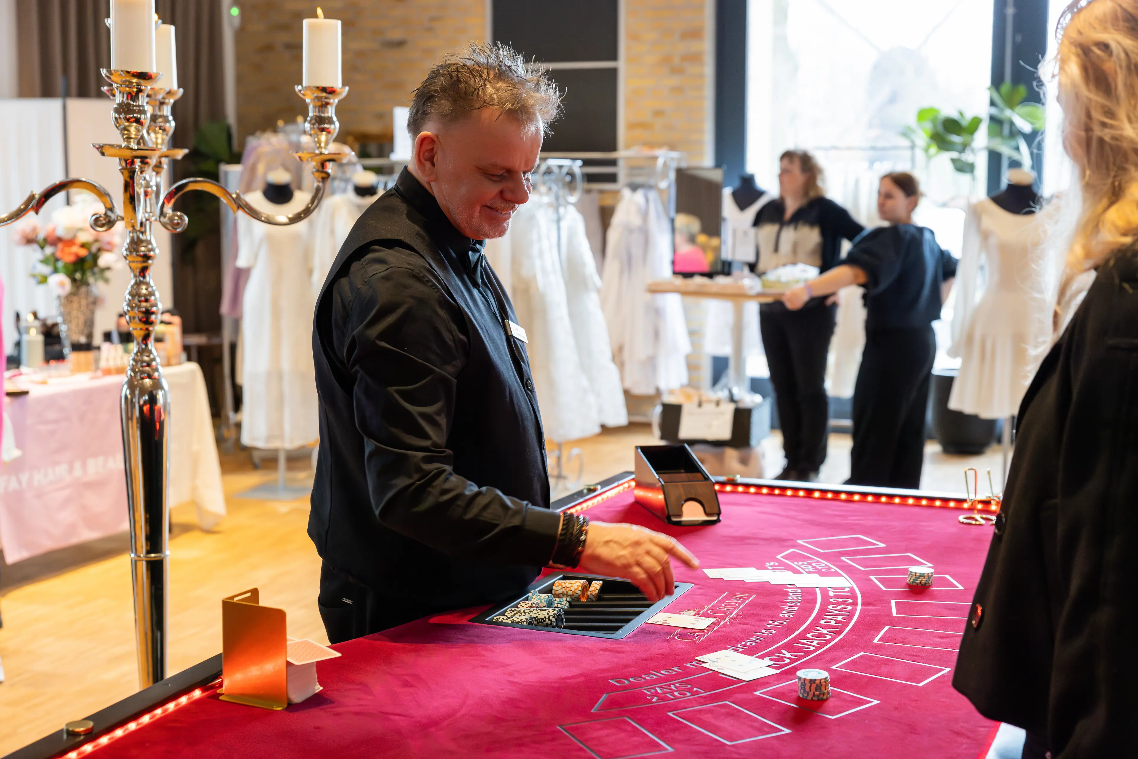 Smilende Casino Crown dealer ved black jack-bord med kandelabrer