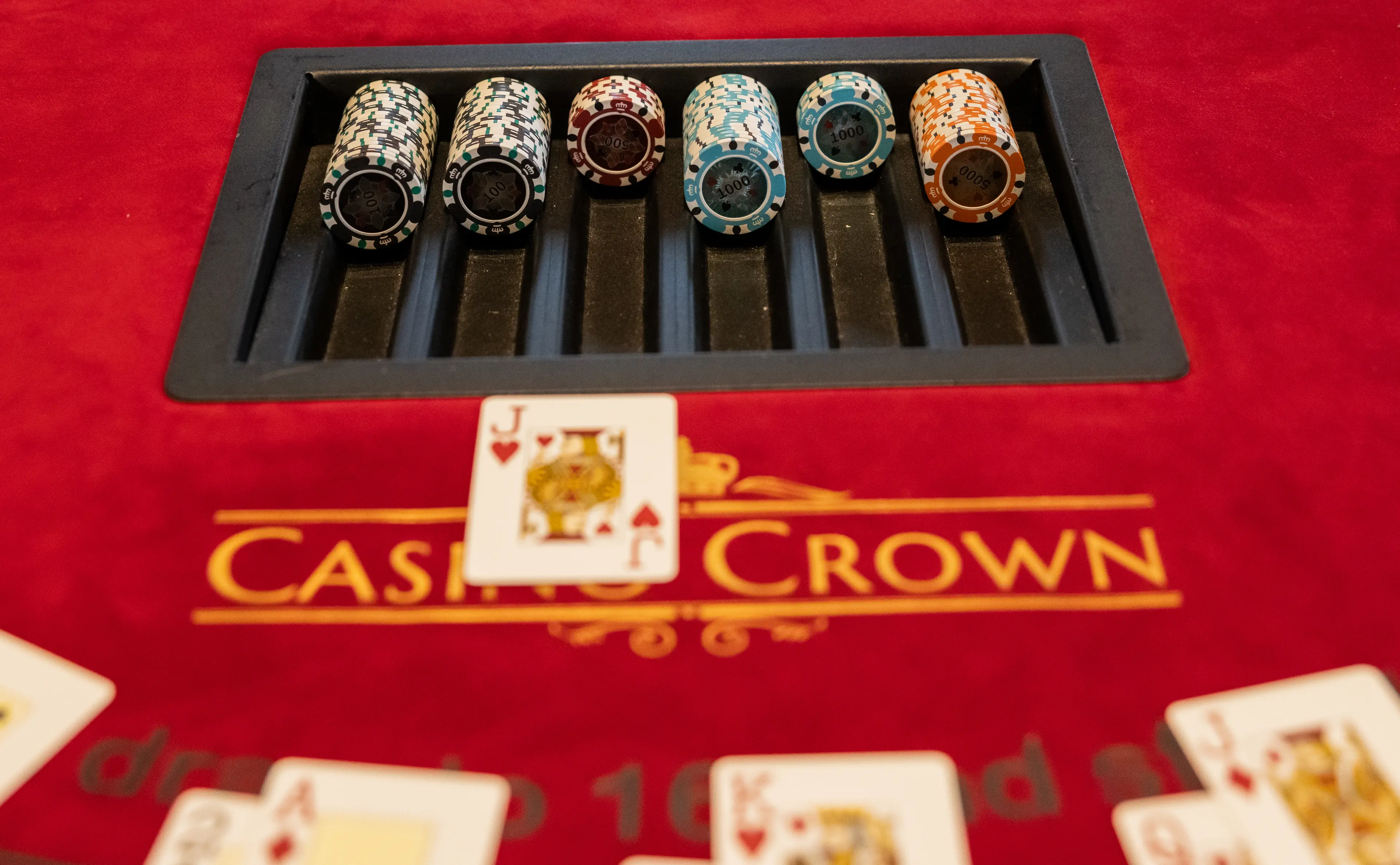 Farverige Casino Crown chips og spillekort på rødt bord