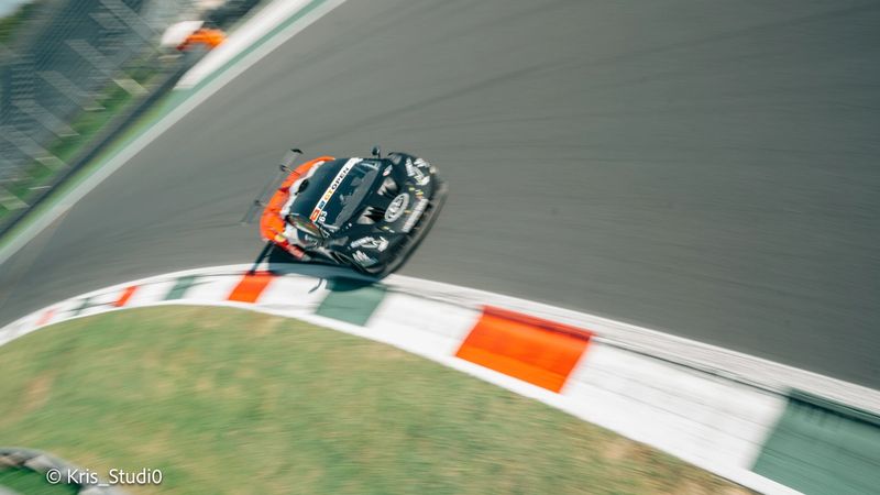 Auto da corsa vista dall'alto in curva, con effetto panning, sul cordolo tricolore
