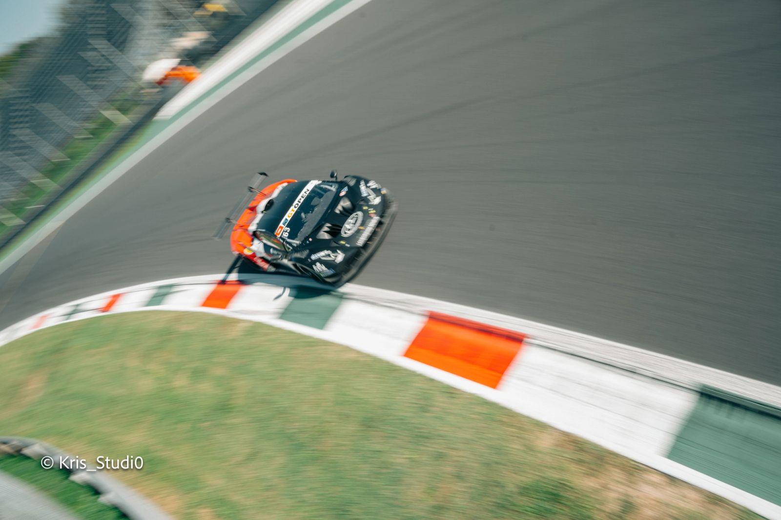 Auto da corsa vista dall'alto in curva, con effetto panning, sul cordolo tricolore
