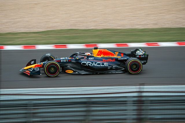 Monoposto di Formula 1 blu e gialla in corsa, ripresa in panning davanti ai cordoli rossi e bianchi