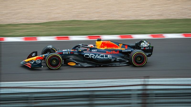 Monoposto di Formula 1 blu e gialla in corsa, ripresa in panning davanti ai cordoli rossi e bianchi