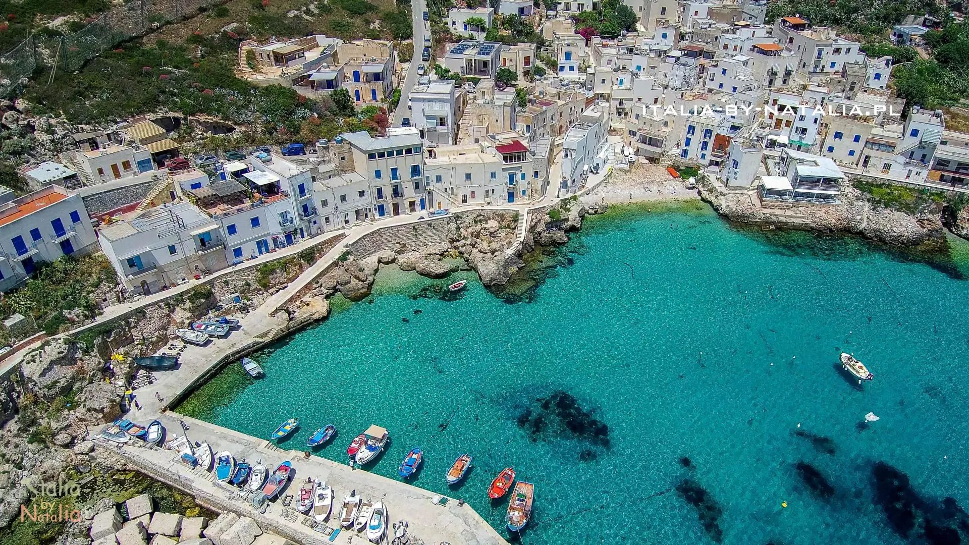 Veduta aerea di un villaggio di case bianche su una baia dall'acqua turchese, con barche ormeggiate