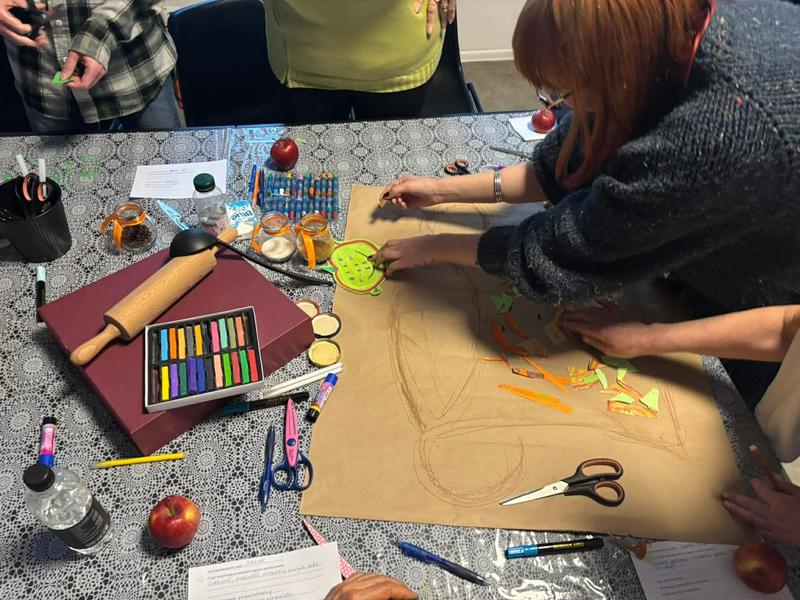 Wspólna praca przy stole nad dużym arkuszem podczas warsztatów