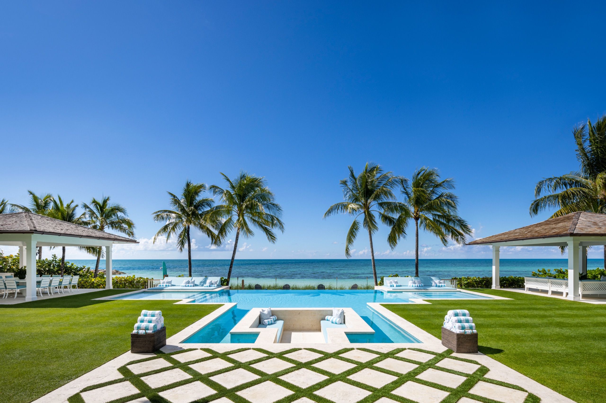 Beachfront lawn and pool framed by palms