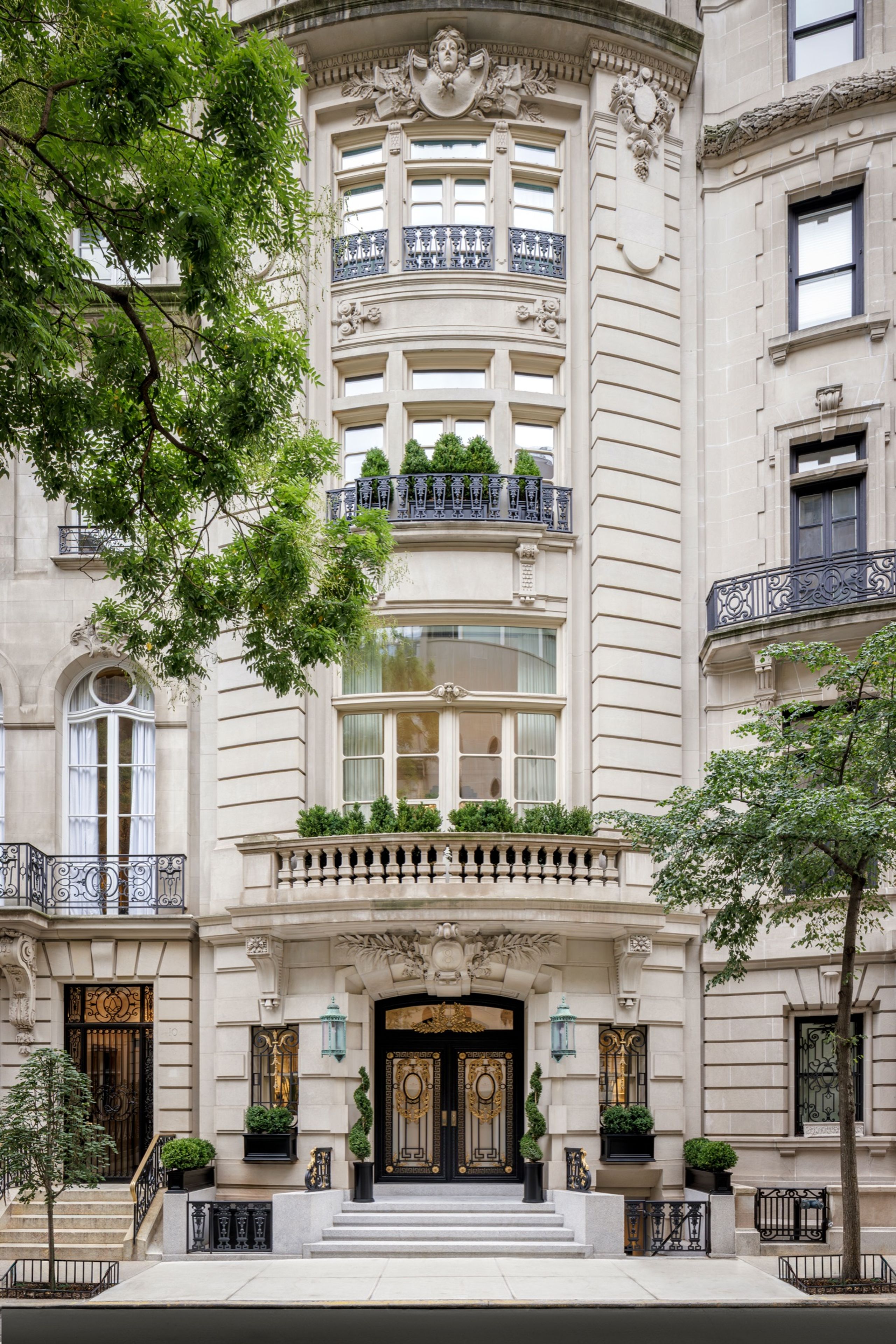 Limestone townhouse facade on a tree-lined street