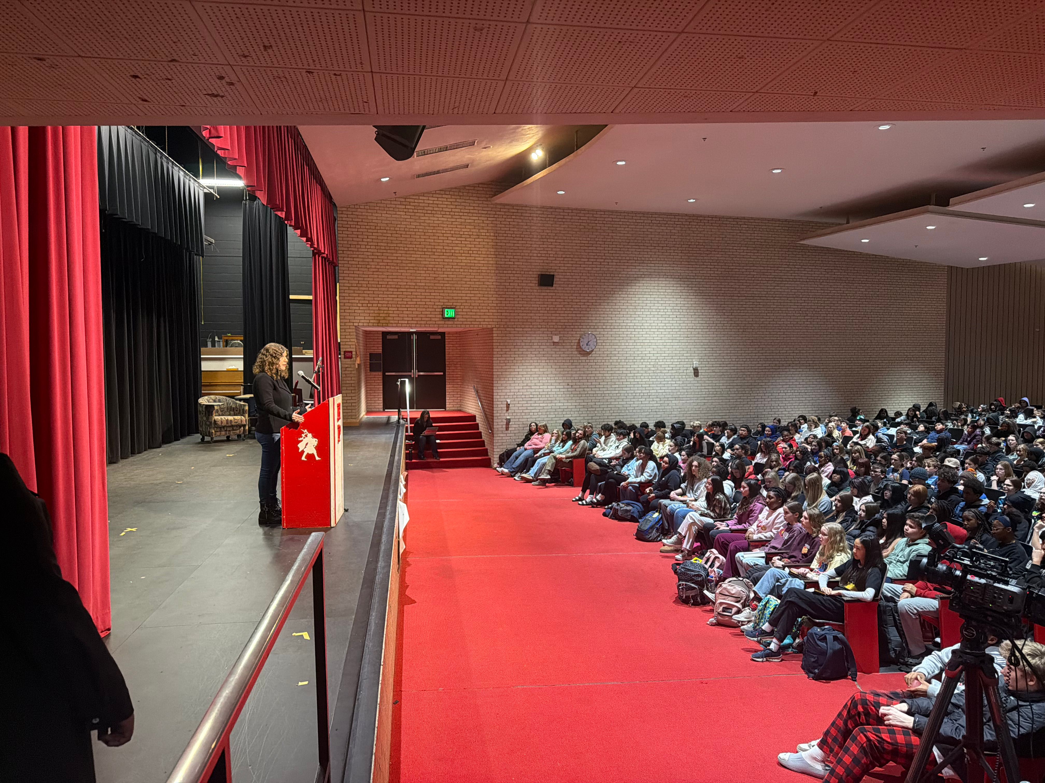 Romina speaking to many students in a large auditorium