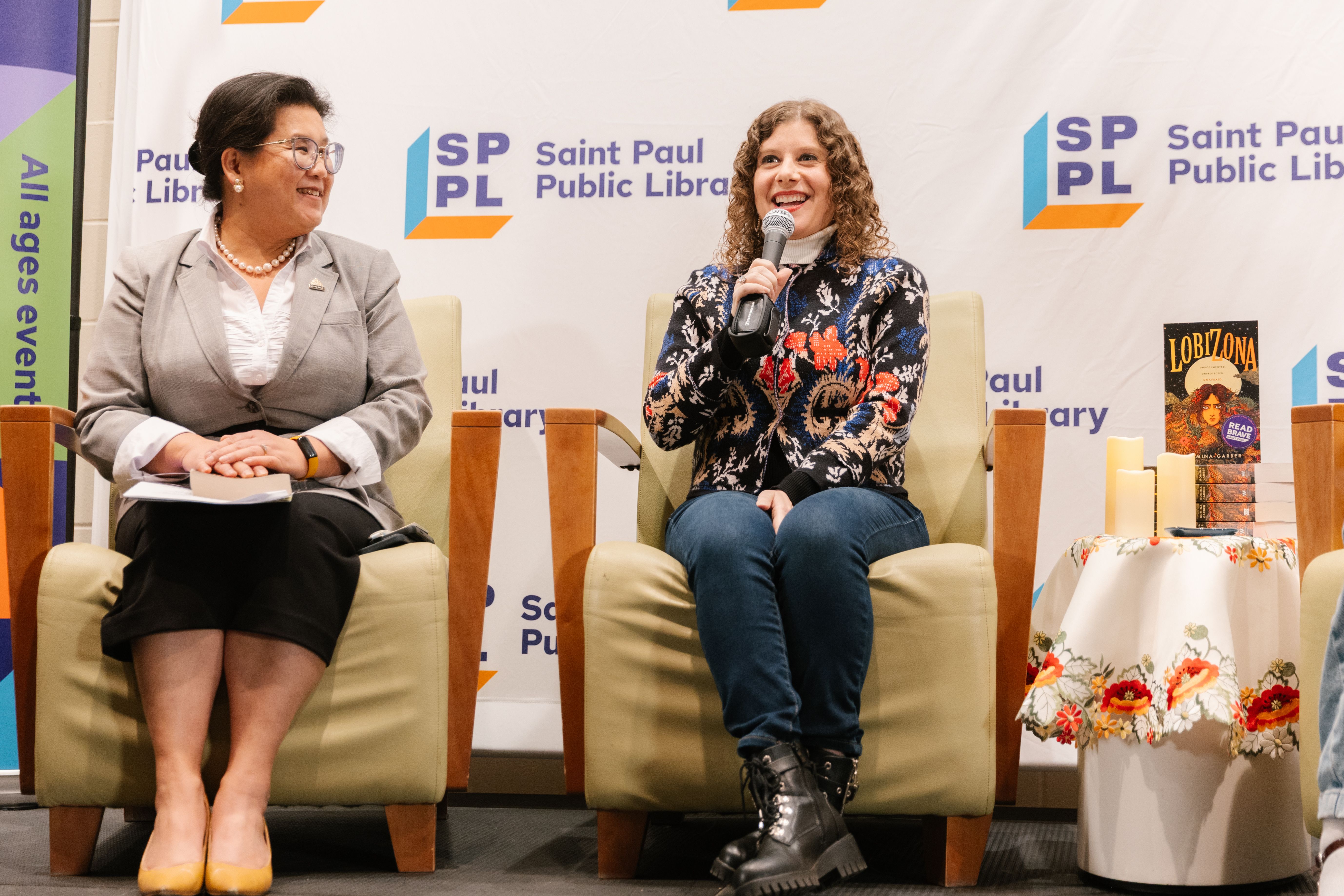 Romina sitting on stage at Saint Paul Public Library
