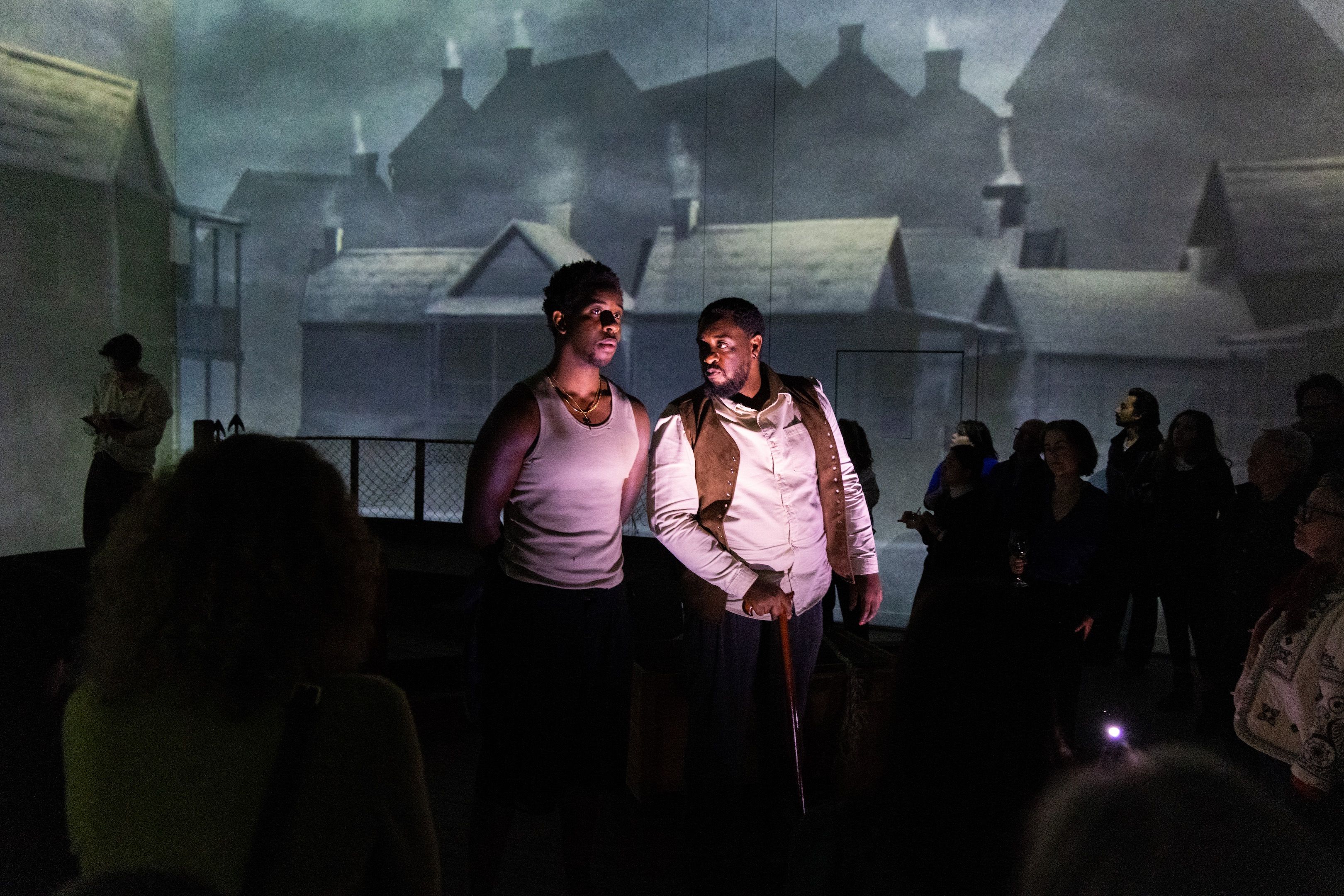 Two men stood on stage with projected backdrop of buildings behind them